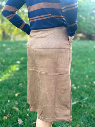 Close-up back view of a camel-brown midi skirt with horizontal panel seams and a gently flared hem.