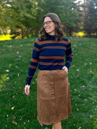 Front view of a model wearing a camel-brown button-front midi skirt with a navy and brown striped sweater.