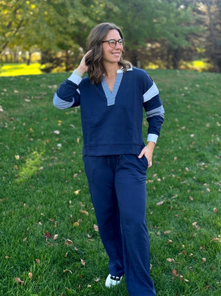 Front view of a navy V-notch collar sweatshirt with striped sleeve stripes, worn with matching wide-leg pants.