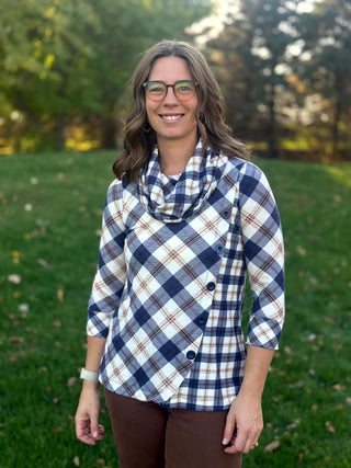 Front view of a navy and cream plaid top with a draped cowl neck, asymmetrical button-front panel, and three-quarter sleeves.