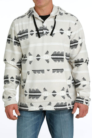 Person wearing a patterned hoodie with geometric design on a white background