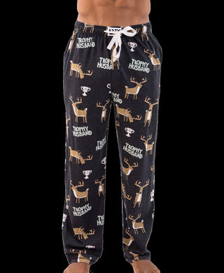 Black pajama pants with deer and 'Trophy Husband' print on a black background