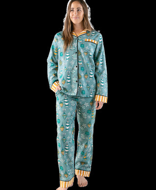 Woman wearing a teal pajama set with festive designs on a black background