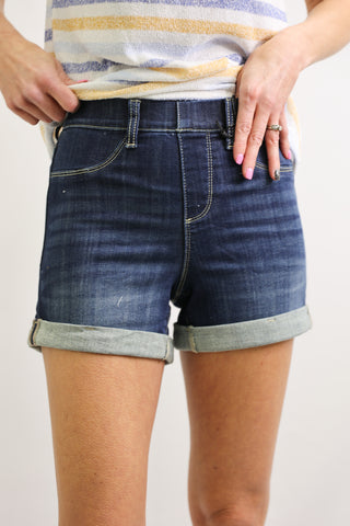 Person wearing blue denim shorts with a plain background