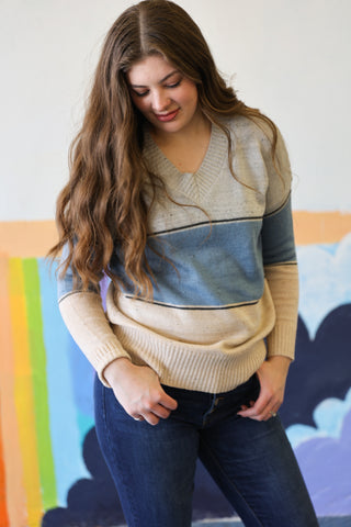 Woman wearing a two-tone sweater in front of a colorful abstract painting