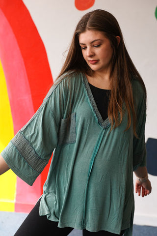 Woman wearing a teal cardigan over a black top against a colorful abstract background