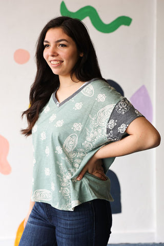 Woman wearing a light green patterned shirt with a colorful abstract painting in the background