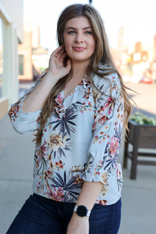 Woman wearing a floral blouse with a blurred outdoor background