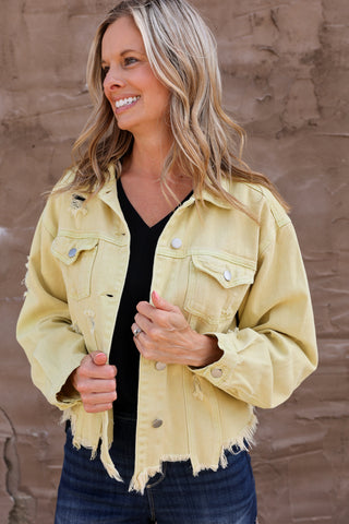 Woman wearing a yellow denim jacket against a brown wall