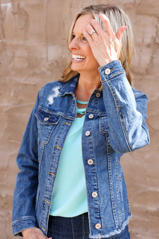 Woman wearing a blue denim jacket against a beige wall
