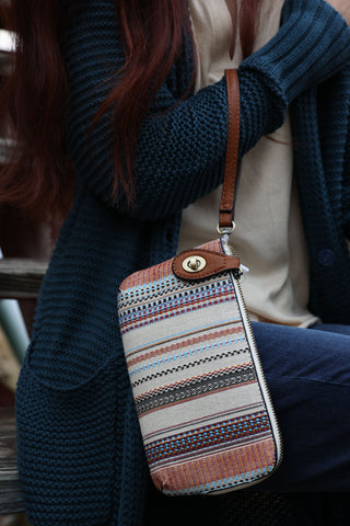Patterned handbag with brown strap on a white background