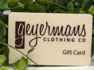 A plastic gift card with the Geyermans Clothing Co. logo and the text 'Gift Card' on it, placed against a leafy green background.