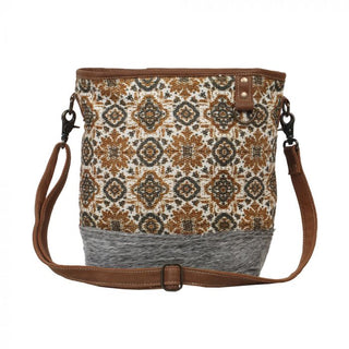 Patterned bag with brown strap and gray base on a white background