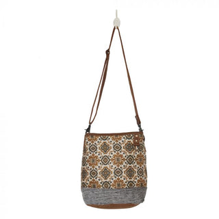 Patterned bag with brown strap and gray base on a white background