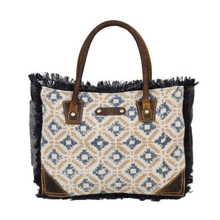 Handbag with patterned fabric and brown leather accents on a white background