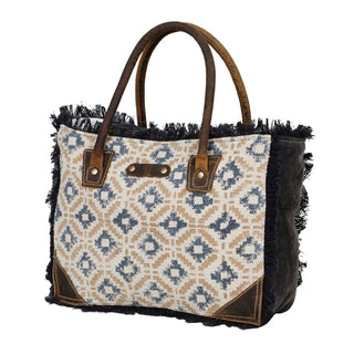 Handbag with patterned fabric and brown leather accents on a white background