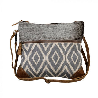 Crossbody bag with gray and white patterned design and brown leather accents on a white background