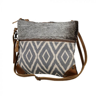 Crossbody bag with gray and white patterned design and brown leather accents on a white background