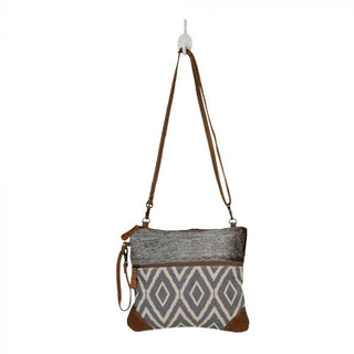Crossbody bag with gray and white patterned design and brown leather accents on a white background