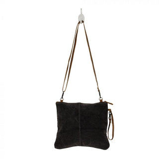 Crossbody bag with gray and white patterned design and brown leather accents on a white background