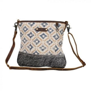 Patterned handbag with brown leather accents on a white background