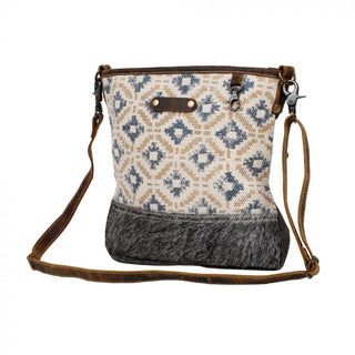 Patterned handbag with brown leather accents on a white background