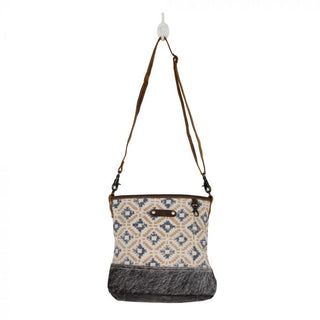 Patterned handbag with brown leather accents on a white background