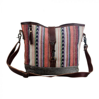 Multicolored striped bucket bag with brown leather accents on a white background