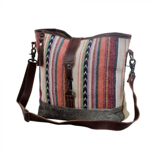 Multicolored striped bucket bag with brown leather accents on a white background