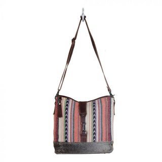 Multicolored striped bucket bag with brown leather accents on a white background