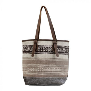 Tote bag with patterned design and brown straps on a white background