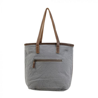 Tote bag with patterned design and brown straps on a white background